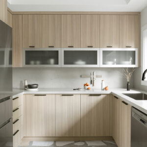 A bright, modern kitchen featuring flat-panel light wood cabinetry accented with minimalist matte black edge pulls. A unique row of horizontal frosted glass cabinets is positioned above a white quartz countertop and a matching seamless slab backsplash fitted with a magnetic knife strip. The space is grounded by a striking large-scale terrazzo floor featuring oversized fragments of white, black, and brown marble. Stainless steel appliances, including a refrigerator and dishwasher, complete the contemporary design.
